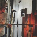 Kobieta trzymająca metalową prętkę, stojąca przy ogniu