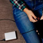 Środkowa sekcja kobiety ładującej telefon komórkowy za pomocą przenośnego ładownika