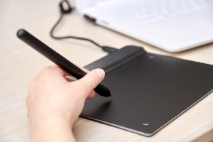 Dziewczyna rysuje na tablecie graficznym za pomocą pióra