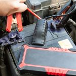 Ręce mechanika samochodowego za pomocą przenośnego rozrusznika samochodowego do rozruchu silnika