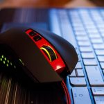 Zbliżenie czerwonej i czarnej myszy komputerowej na klawiaturze laptopa na stole