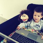 Słodki chłopiec trzymający laptop, siedząc w domu na kanapie.