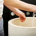 Środkowa sekcja kobiety myjącej ręce w zlewie w łazience