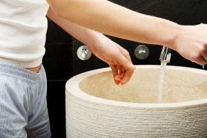 Środkowa sekcja kobiety myjącej ręce w zlewie w łazience