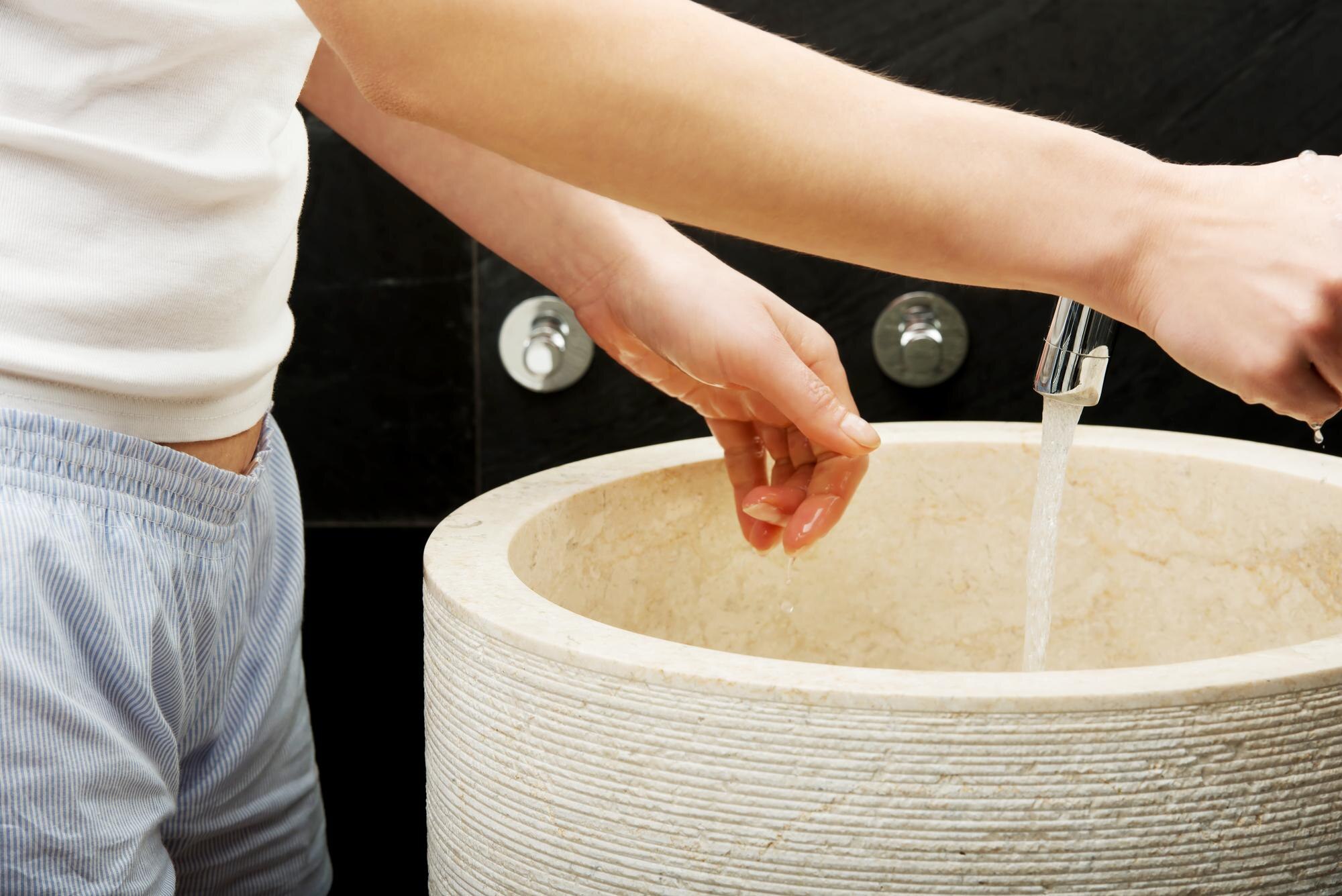 Środkowa sekcja kobiety myjącej ręce w zlewie w łazience