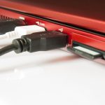 Zbliżenie kabli USB podłączonych do laptopa na białym tle