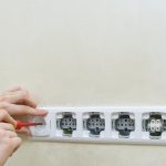 Środkowa sekcja kobiety trzymającej kamerę na białej ścianie