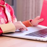 Azjatycki chłopiec w chińskich tradycyjnych ubraniach trzymający czerwoną paczkę pieniędzy przed laptopem i rozmową wideo