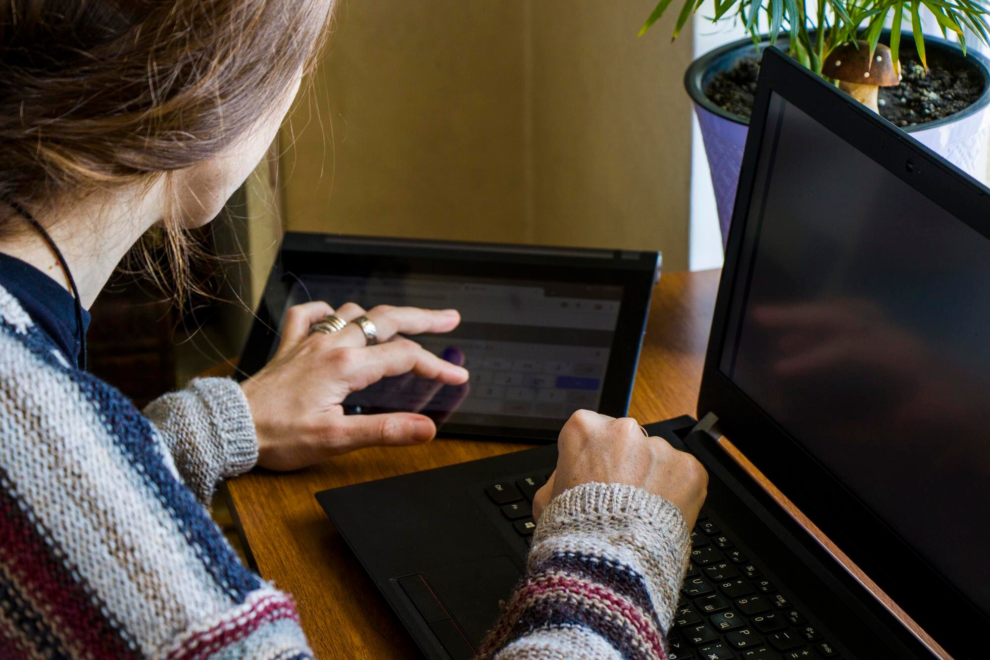 Kobieta pracująca w biurze z cyfrowym tabletem i notebookem pisząc i pisząc na urządzeniu