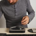 Otwarty komputer osobisty na białym stole w laboratorium naprawy usług elektronicznych, mistrz bierze sterownik bitowy