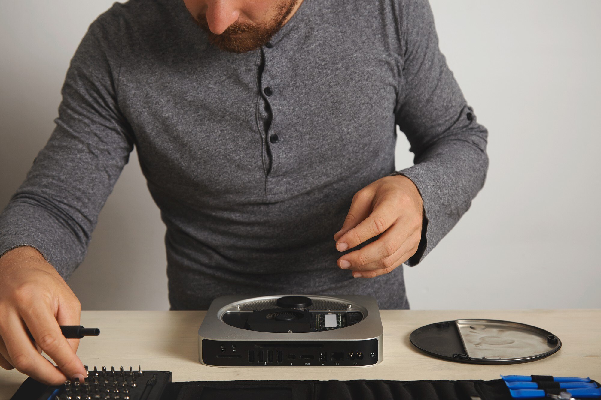 Otwarty komputer osobisty na białym stole w laboratorium naprawy usług elektronicznych, mistrz bierze sterownik bitowy