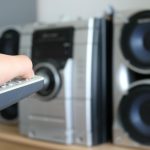 Przycięta ręka trzymająca zdalnie sterowany urządzenie przed urządzeniem audio