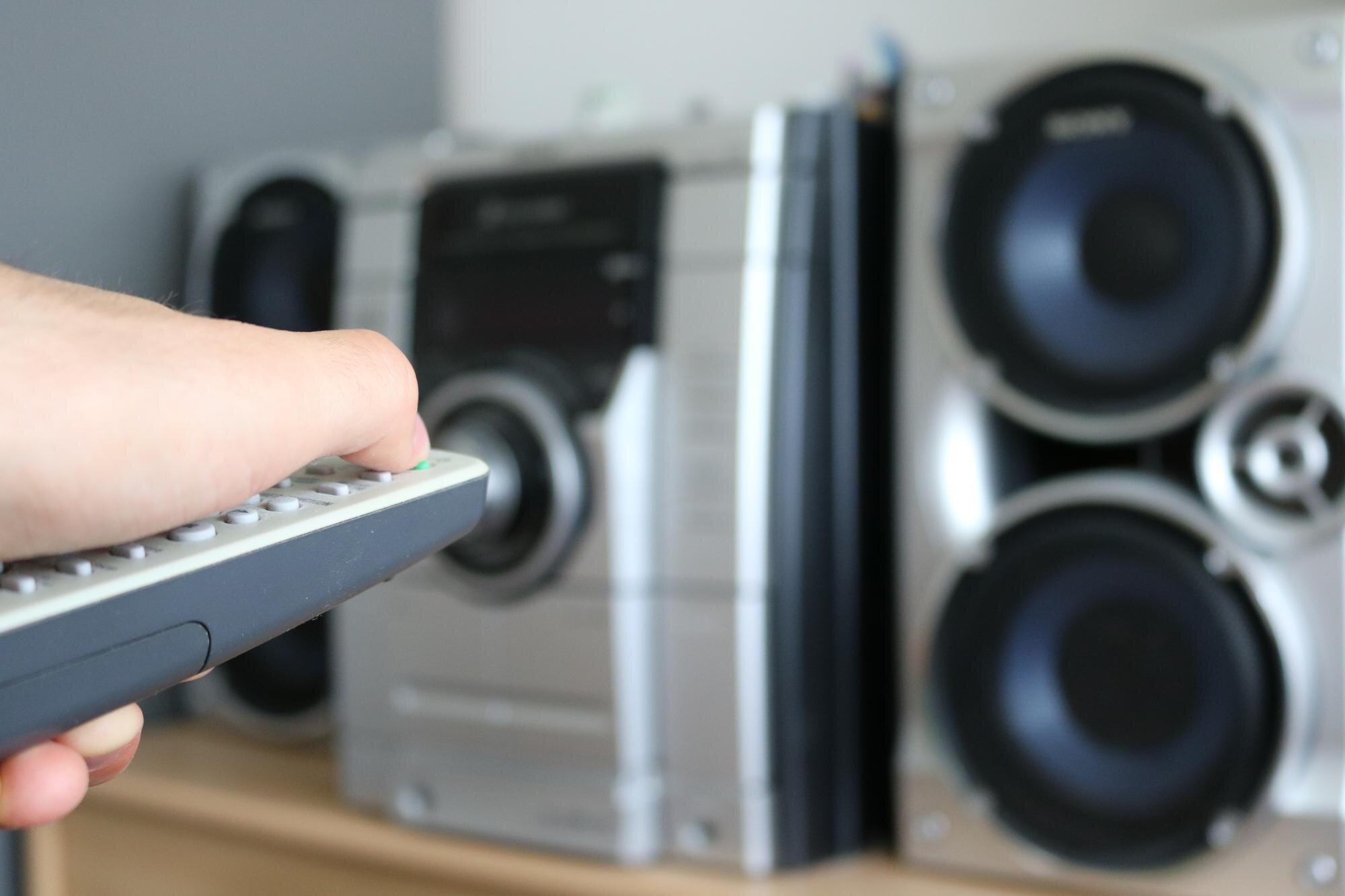 Przycięta ręka trzymająca zdalnie sterowany urządzenie przed urządzeniem audio