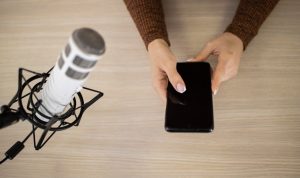 Widok z góry kobiety w studio radiowym ze smartfonem i mikrofonem