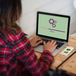 Z tyłu widok kobiety używającej laptopa na stole