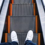 Dolna część osoby stojącej na schodach ruchomych
