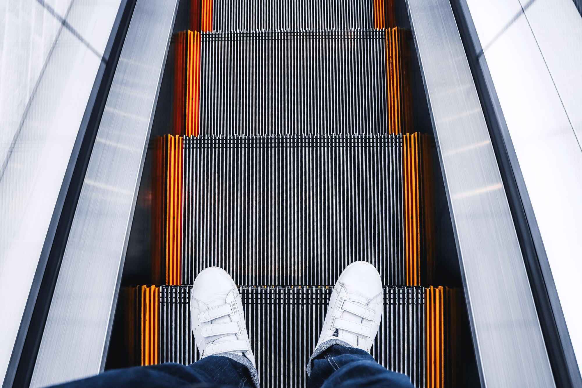 Dolna część osoby stojącej na schodach ruchomych