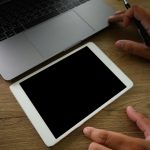 Dolna część osoby używającej telefonu komórkowego na stole