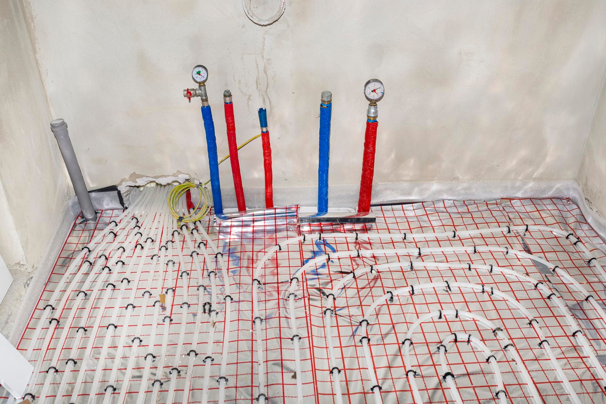 Rury z ciepłą i zimną wodą wychodzącą z podłogi i manometry zamontowane na końcach