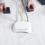 Router internetowy na biurku. Osoby korzystające ze smartfonów
