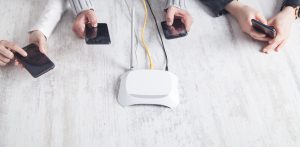 Router internetowy na biurku. Osoby korzystające ze smartfonów