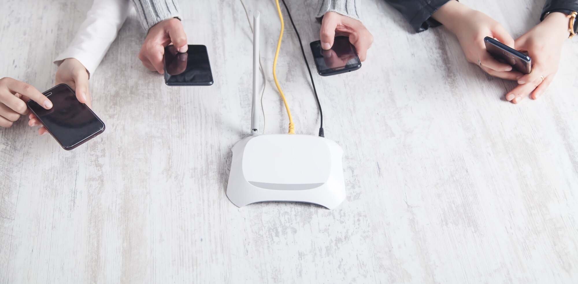 Router internetowy na biurku. Osoby korzystające ze smartfonów