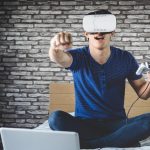 Mężczyzna grający w grę wideo z symulatorem wirtualnej rzeczywistości na łóżku