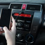 Przycięty obraz ręki używającej laptopa w samochodzie