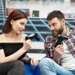 Portret wesołej, aktywnej pary grającej w gry wideo na playstation z kontrolerem konsoli w dłoniach, fani Xboxa