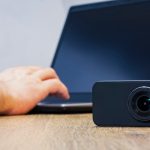 Kamera akcji na stole na tle mężczyzny pracującego przy laptopie.