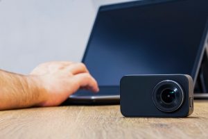 Kamera akcji na stole na tle mężczyzny pracującego przy laptopie.