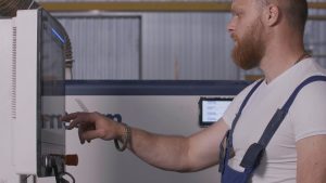 Mężczyzna klika panel sterowania kreatywnego mężczyzny w mundurze i dostosowuje panel w fabryce