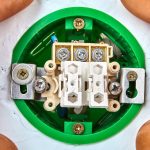 Okrągły zielony przycisk standardu europejskiego w trakcie montażu w ścianie gipsowej.