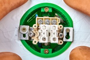 Okrągły zielony przycisk standardu europejskiego w trakcie montażu w ścianie gipsowej.