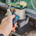 Mężczyzna ręcznie naciskający na zdalny sterowanie, aby otworzyć drzwi bramy