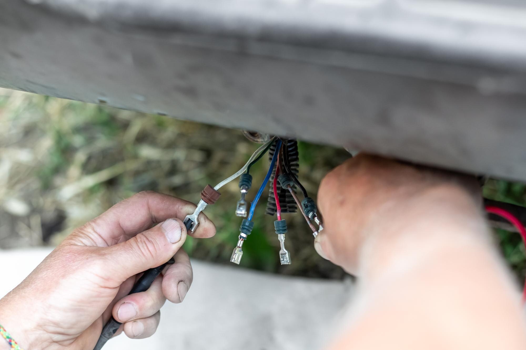 a man holds in his hands wires with terminals for connecting rear brake lights to a car towbar Electrical wiring for trailer