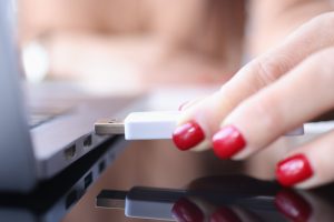 Ręka kobiety wkłada pamięć flash USB do złącza laptopa