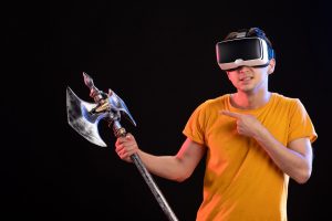 Portret młodego mężczyzny grającego w vr z toporem bojowym na ciemnej ścianie