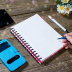 Ludzka ręka trzymająca ołówek typu clutchtype z otwartym notatnikiem