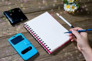 Ludzka ręka trzymająca ołówek typu clutchtype z otwartym notatnikiem