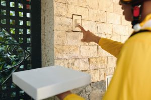 Kurier z pizzą dzwoniącym dzwonkiem.