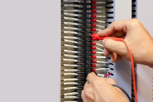 Zbliżenie dłoni elektrotechniki za pomocą pomiaru do sprawdzania energii elektrycznej.