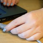 Ręka kobiety łączy konektor sieciowy RJ45 z laptopem