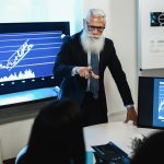 Wielopokoleniowy zespół traderów przeprowadzający konferencję na temat analizy giełdowej w biurze funduszu hedgingowego - Skoncentruj się na twarzy starszego mężczyzny