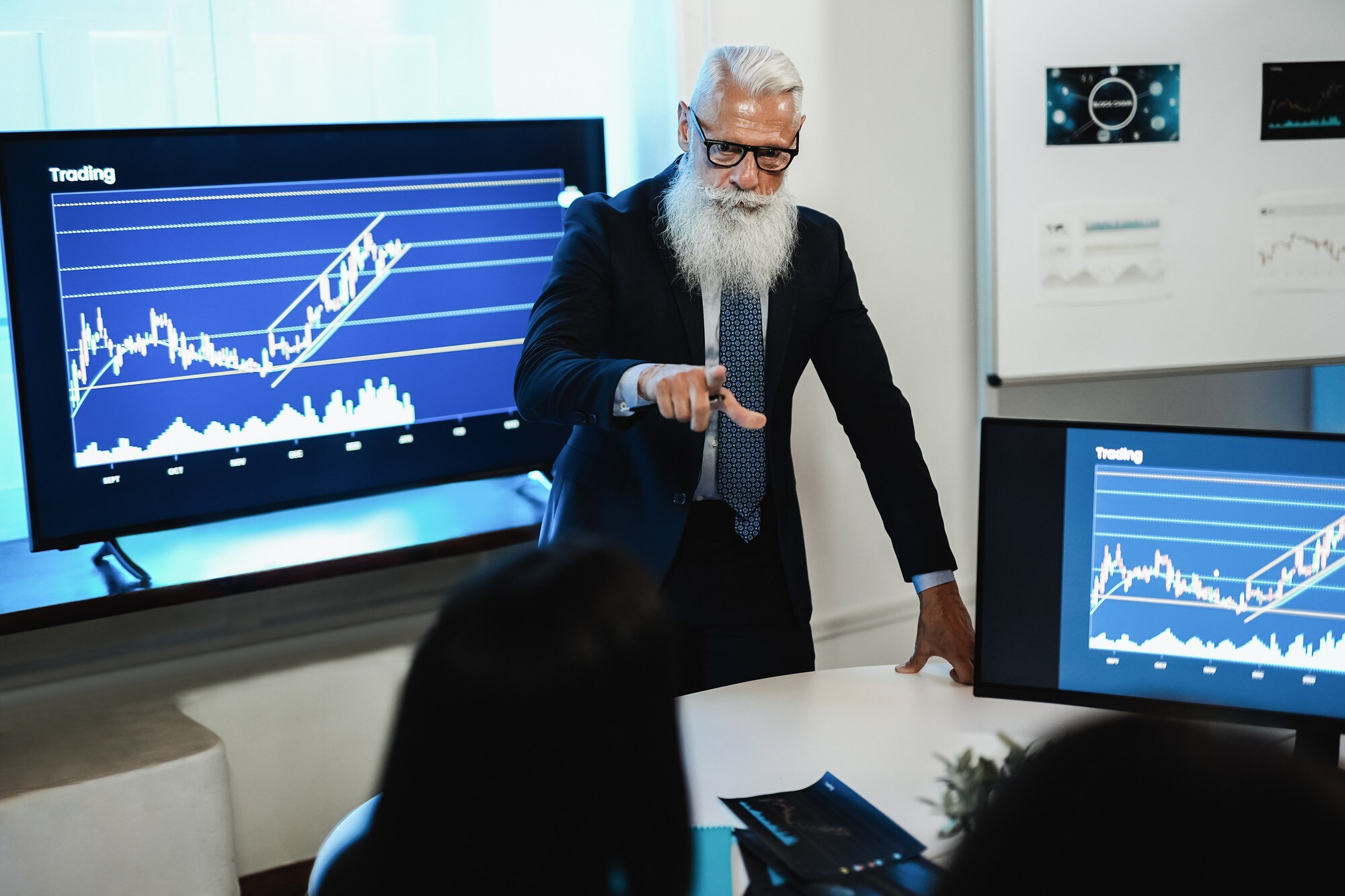 Wielopokoleniowy zespół traderów przeprowadzający konferencję na temat analizy giełdowej w biurze funduszu hedgingowego - Skoncentruj się na twarzy starszego mężczyzny