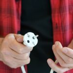 Męskie dłonie ze złamaną europejską podwójną przedłużaczem elektrycznym do naprawy, rzucania lub zmiany, koncepcja mistrza elektroniki