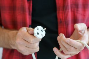 Męskie dłonie ze złamaną europejską podwójną przedłużaczem elektrycznym do naprawy, rzucania lub zmiany, koncepcja mistrza elektroniki