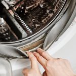 Nierozpoznawalna kobieta czyści pralkę