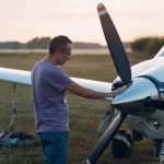 Pilot mężczyzna stojący obok małego prywatnego samolotu.