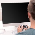 Młody mężczyzna grający w gry komputerowe w domu